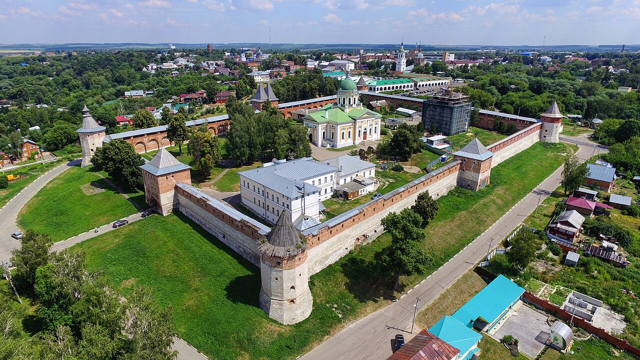 Вид с дрона на Зарайский кремль: кирпичные стены, башни и собор с зелёным куполом летом.