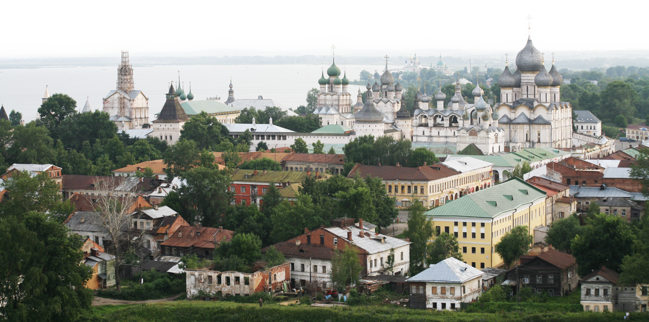 Панорама Ростова Великого с высоты: купола и стены кремля, городская застройка и озеро Неро вдали.