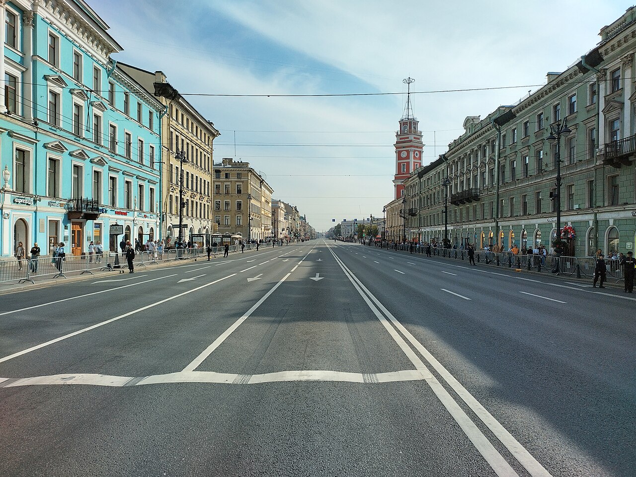 Пустой Невский проспект с яркими фасадами и башней городской думы вдали в солнечный день.